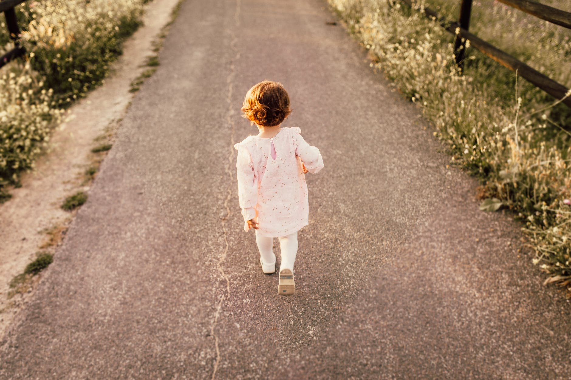 girl wearing white clothes walking on pavement road