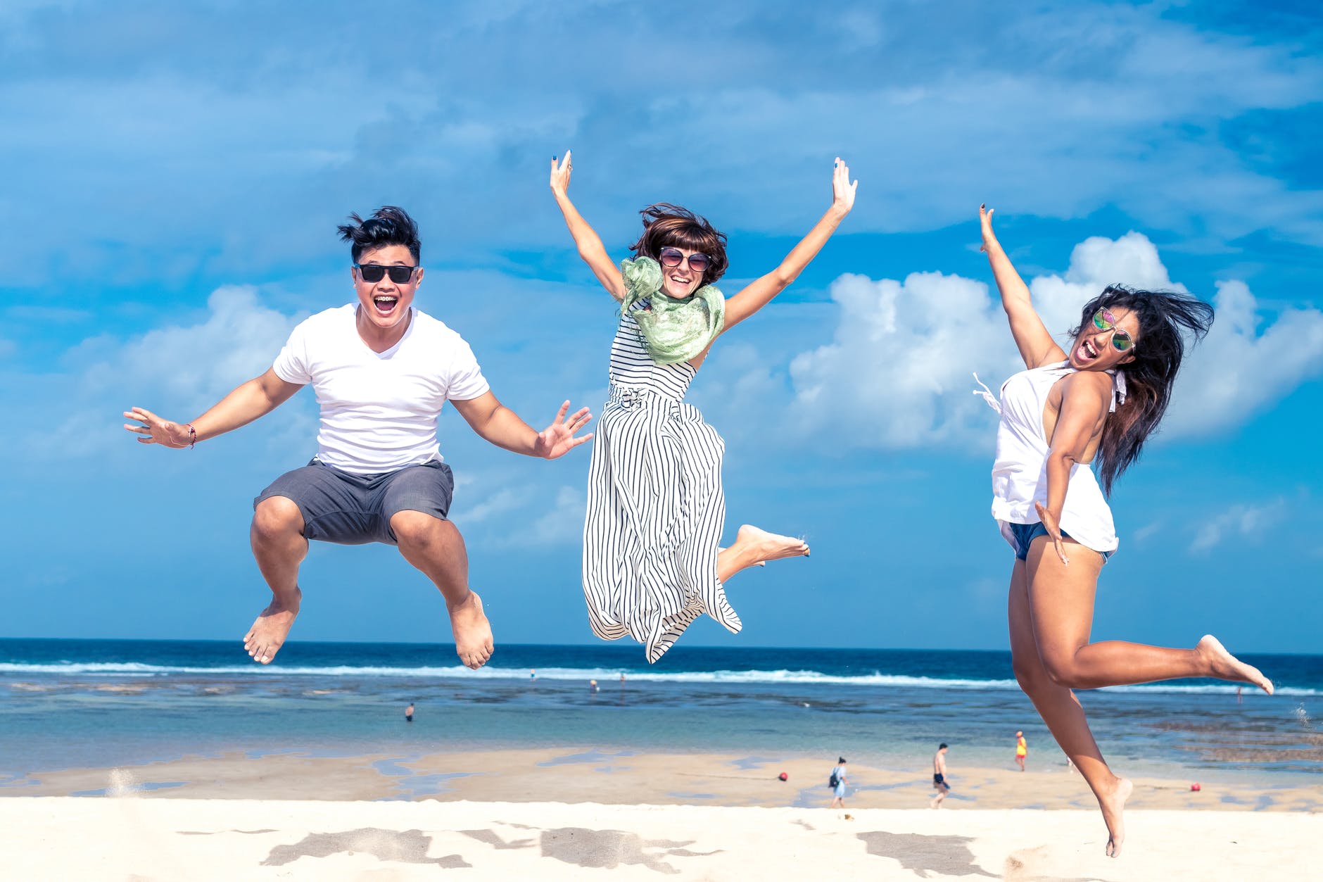 woman and man jumping on seashore