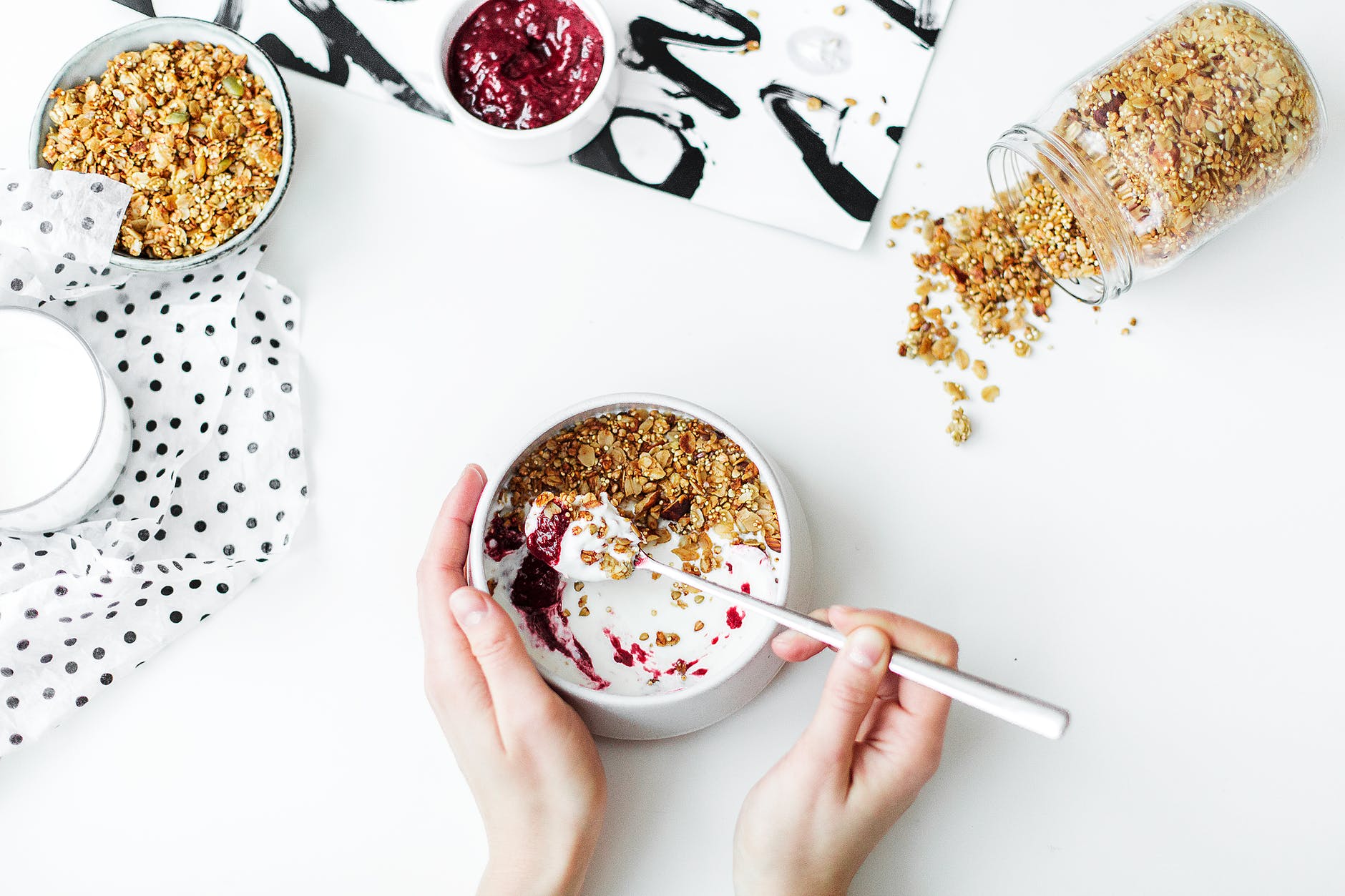 person mixing cereal milk and strawberry jam on white ceramic bowl