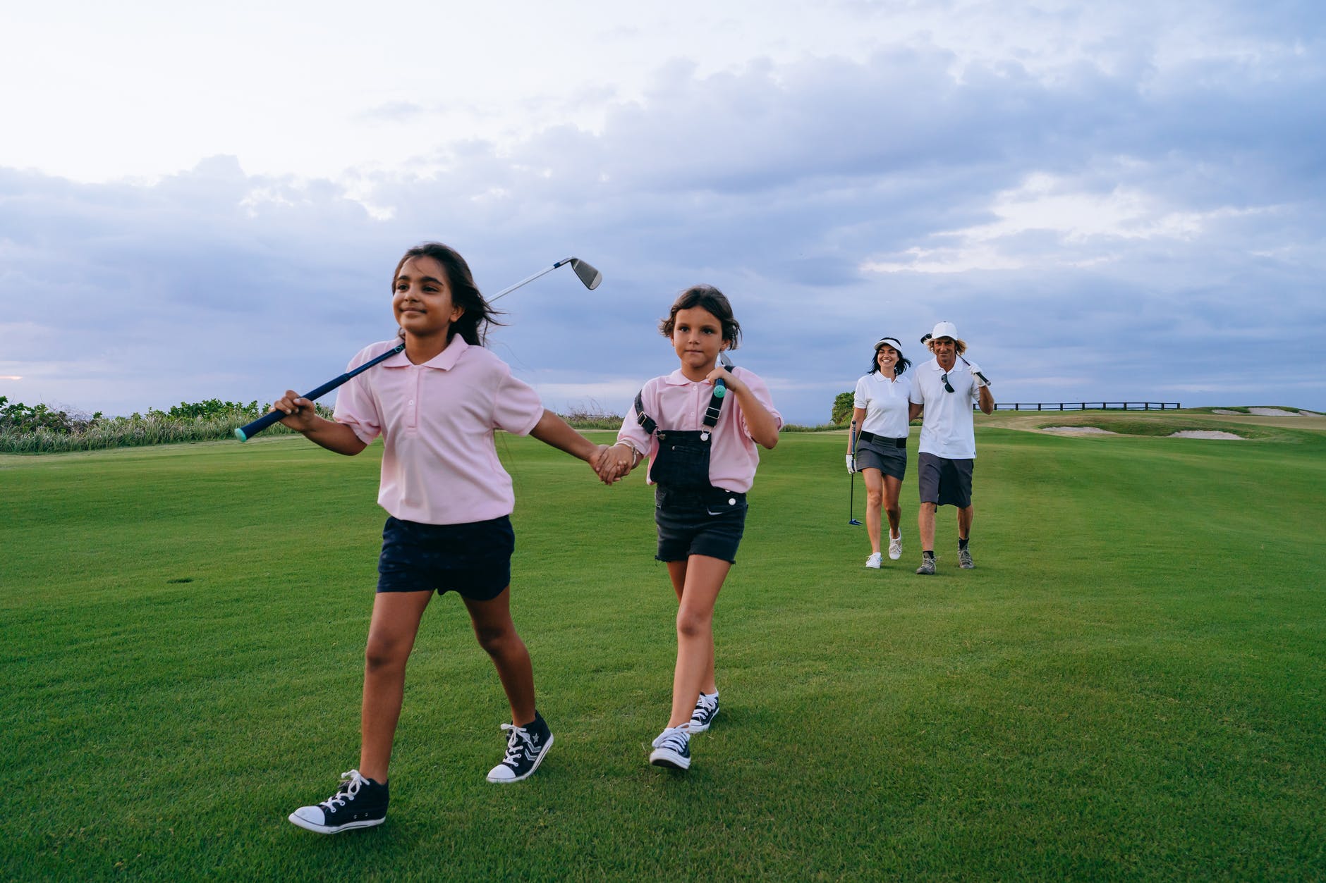 siblings holding each other s hands while carrying a golf club