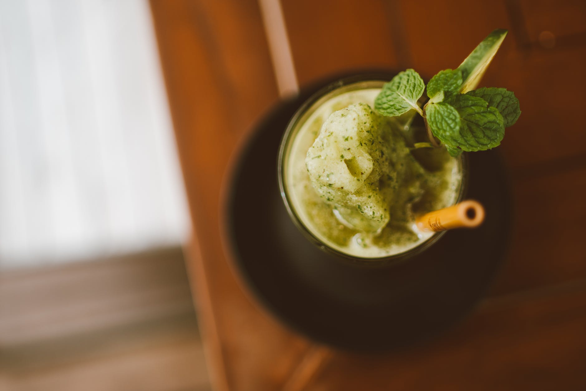 a green smoothie garnished with mint leaves and a slice of cucumber