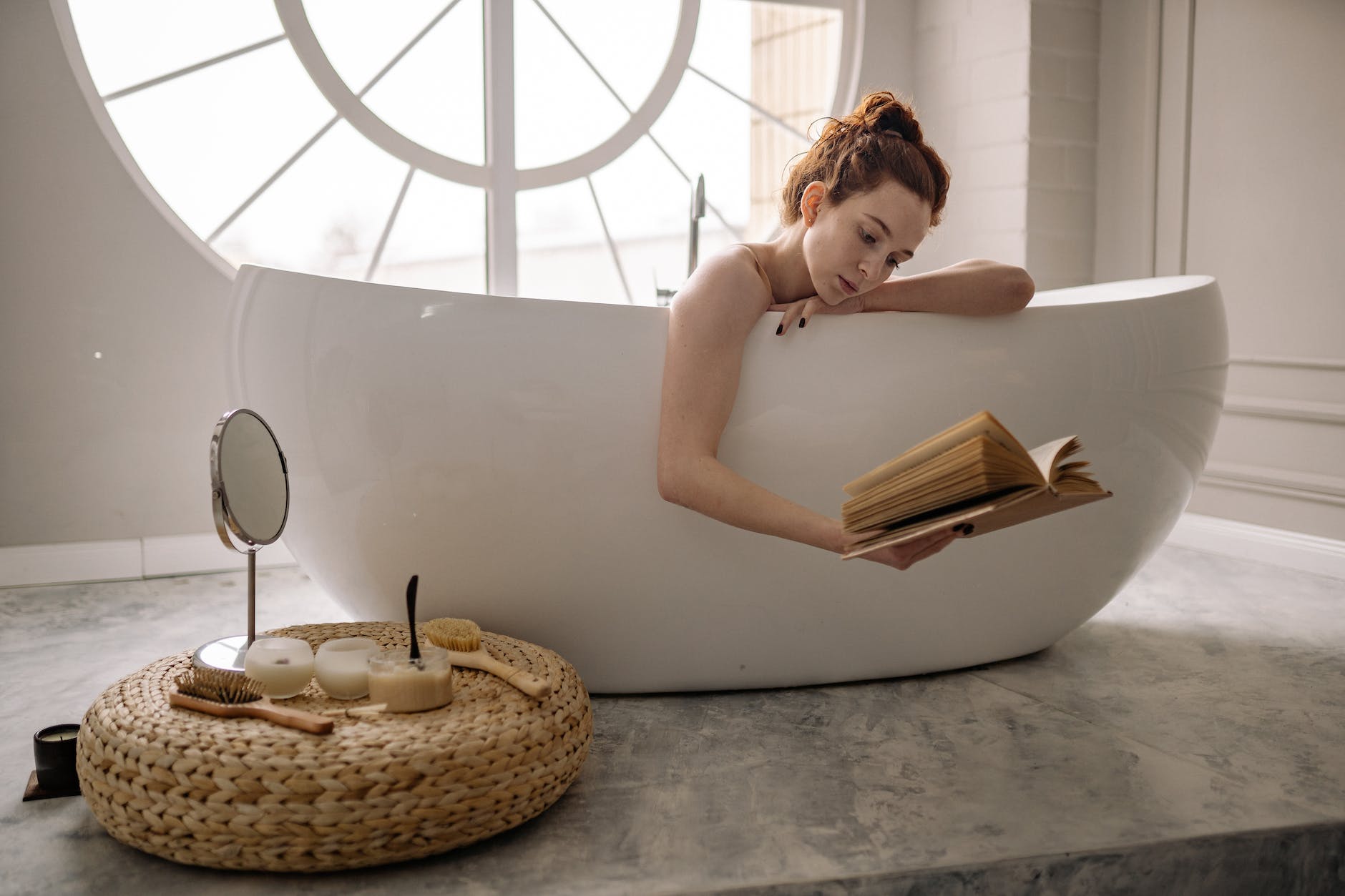 woman on bathtub while reading book